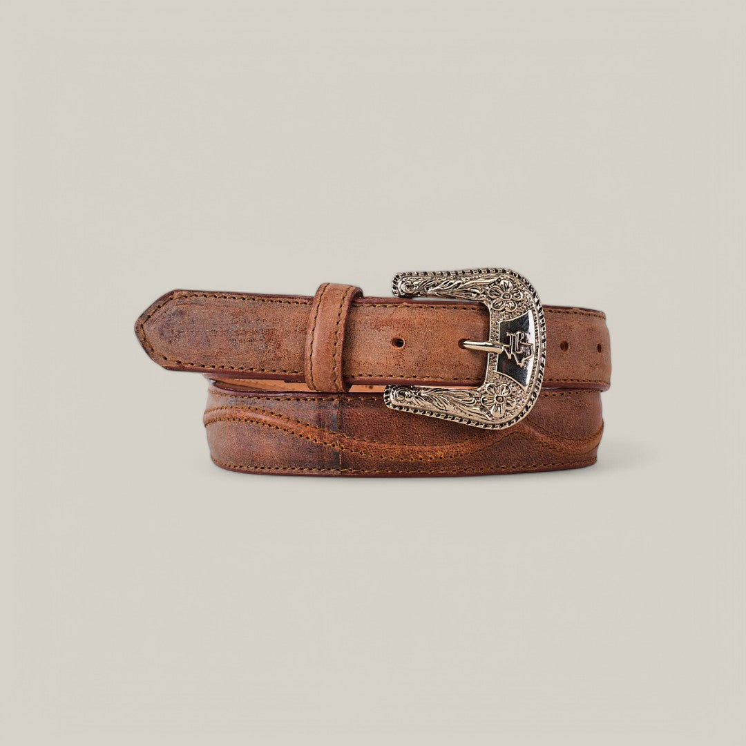 The Isabella Brick Belt - Texas Buckle is a rolled brown leather belt with an ornate silver buckle featuring engraved star motifs on a plain light gray background, making it an elegant fashion accessory.