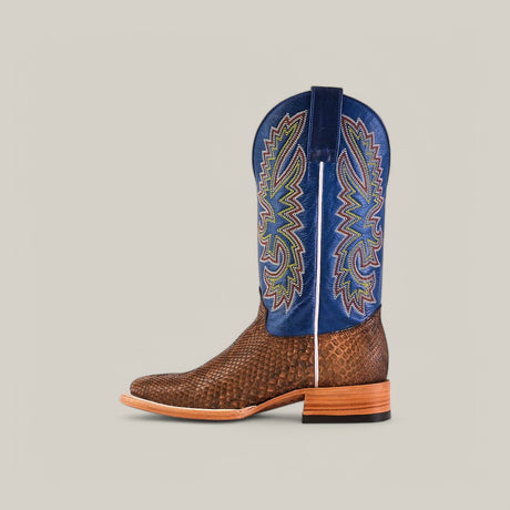The Exotic Python - Tamarindo boot features a textured brown leather foot, a tall blue shaft with colorful embroidery, and a wooden stacked heel. It has a modern square toe and light brown sole set against a neutral gray background.