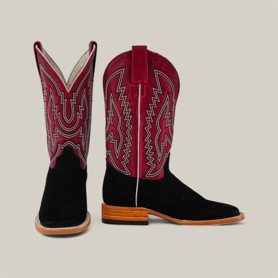 The Black Suede - Platinum - Square Toe boots feature black suede lower sections and red upper shafts with intricate white stitching and zigzag patterns. Platinum accents add elegance, complemented by a wooden heel against a plain beige background.
