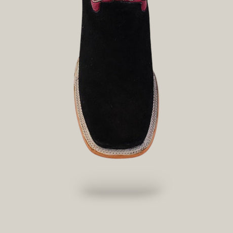 The Black Suede - Platinum - Square Toe boots feature a square toe, light brown sole, and platinum accent near the laces. Styled with western flair, they are showcased against an off-white background.