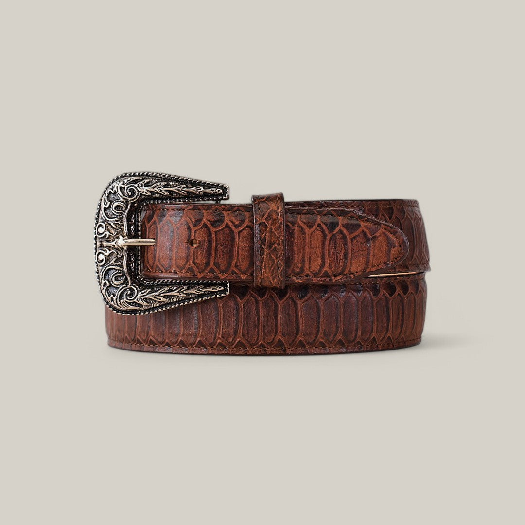 The Python Print Brown - Texas Buckle is a belt with an embossed scale pattern and intricate silver buckle, coiled with the tip through it, set against a gray background for both fashion and function.