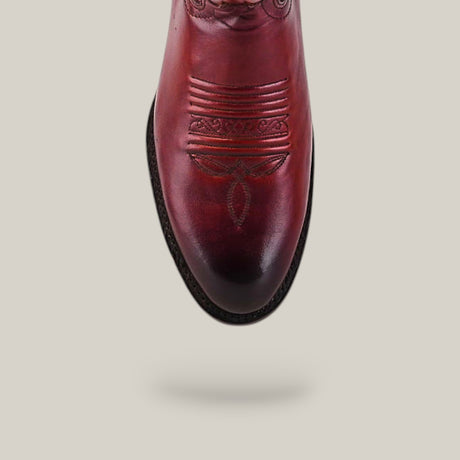 A top view of the Wyatt - Cogñac - Roper Toe boot, a reddish-brown cowhide design featuring decorative toe stitching, highlights its quality craftsmanship against a plain light background.