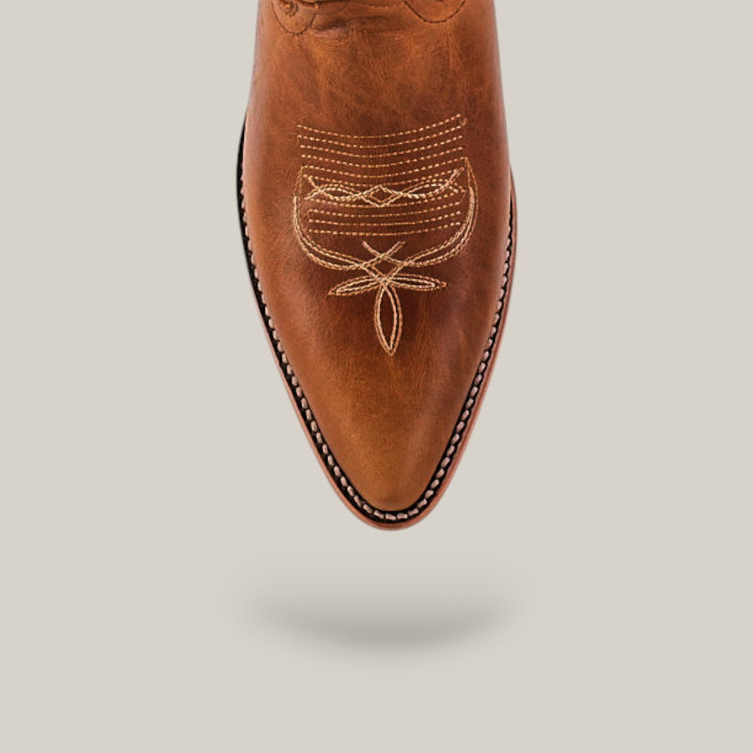 The Fresno - Fawn - Snip Toe boot features premium brown leather, a pointed snip toe, and detailed beige stitching, shown on a light beige background with a subtle shadow, showcasing authentic cowhide craftsmanship.