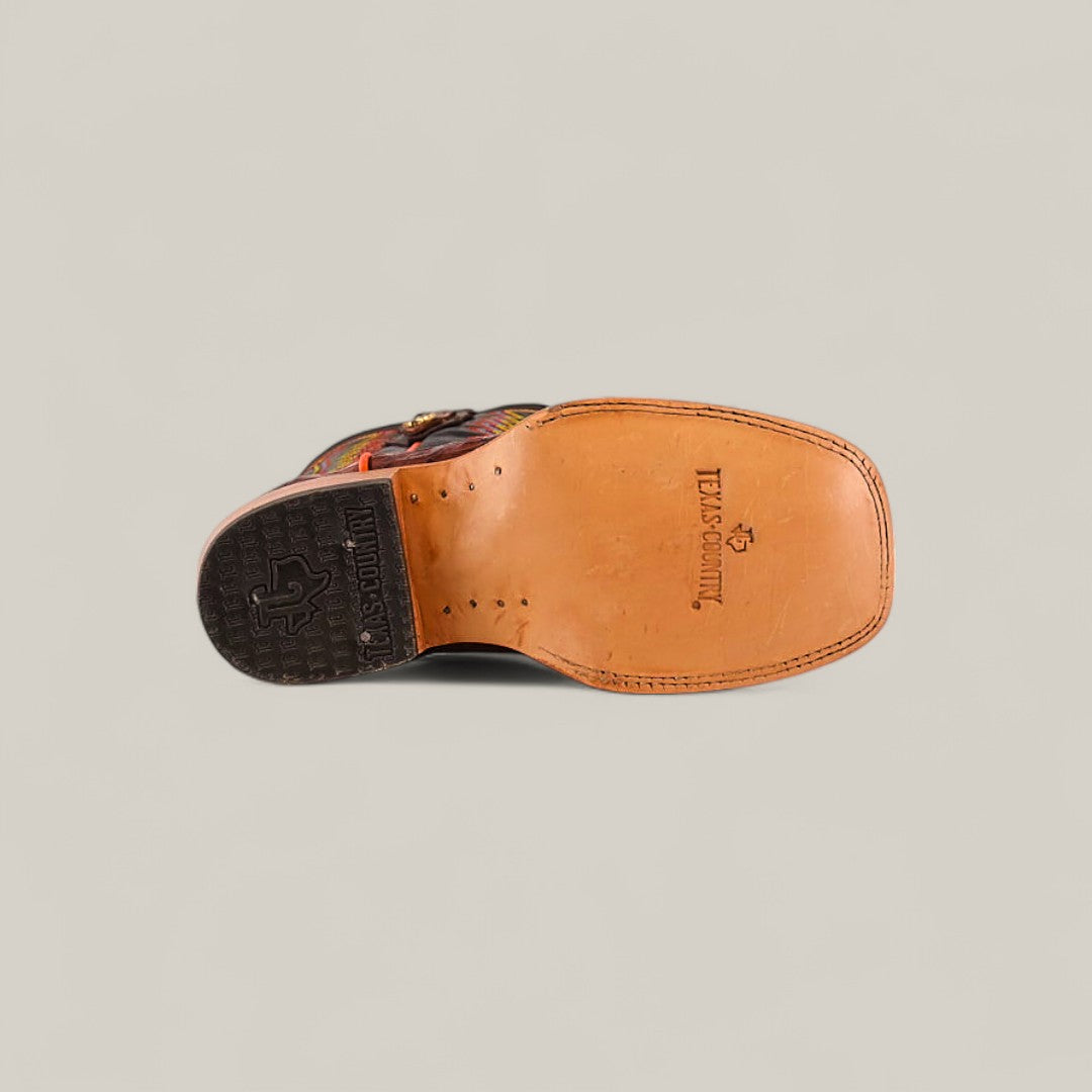 The Exotic Caiman Belly Tail Cognac Square Toe Kids Boots showcase a tan leather sole stamped with TEXAS COUNTRY and logo near the heel, plus a dark, textured heel—ideal for fans of square toe boots.