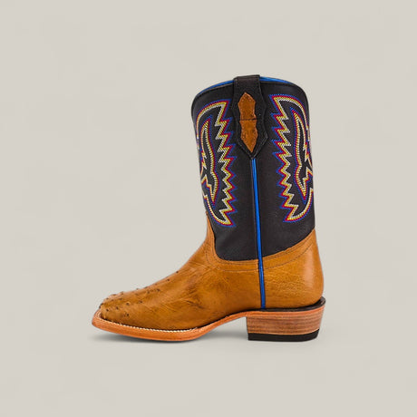 The Exotic Full Quilt Ostrich Fawn Kids Boots feature a brown and black design, colorful embroidery on the shaft, a square toe, and a stacked wooden heel, crafted with Western elegance and shown in side profile against a plain background.