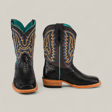 A pair of Exotic Python Black - Square Toe Kids Boots in trendy black python-textured leather with tan soles and vibrant blue, yellow, and orange stitching—one boot shown forward, the other sideways.
