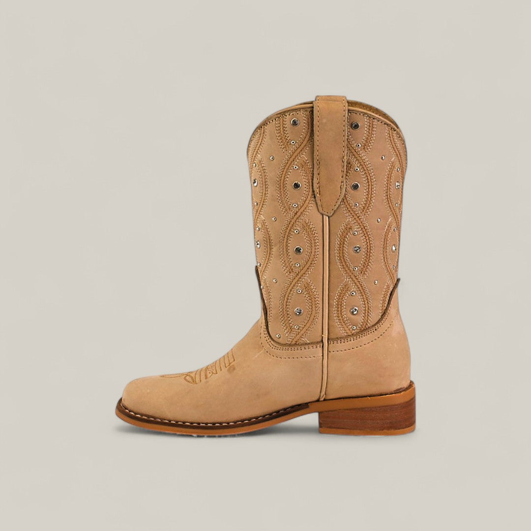 The Premiere Suede Bone - Square Toe Kids boot features premium tan suede, decorative stitching, small silver studs, a wooden heel, and a top loop, shown against a plain light background.