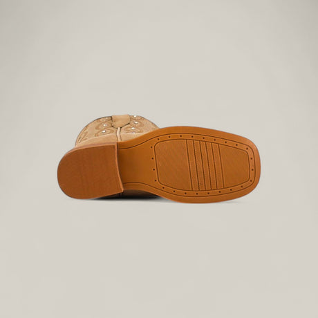 Premiere Suede Bone - Square Toe Kids boots shown from the bottom, displaying their brown rubber sole with textured grip and slight heel. Crafted from premium suede in a bone hue, set against a plain light background.