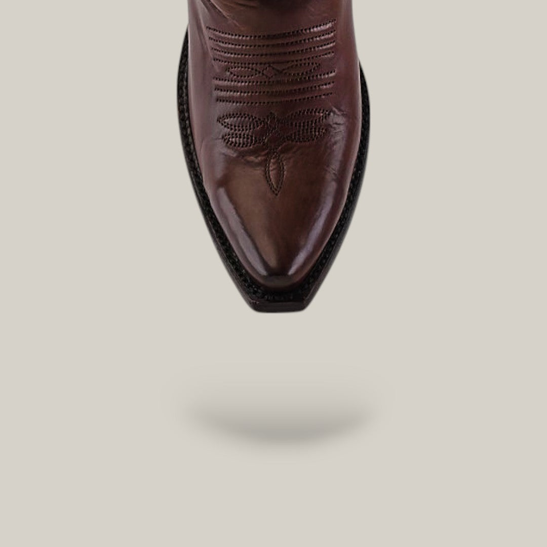 A close-up of the snip toe on the Kellie Clayton Caramel Leather Sole Tall Shaft boot, featuring decorative stitching, set against a plain light background with a soft shadow beneath.