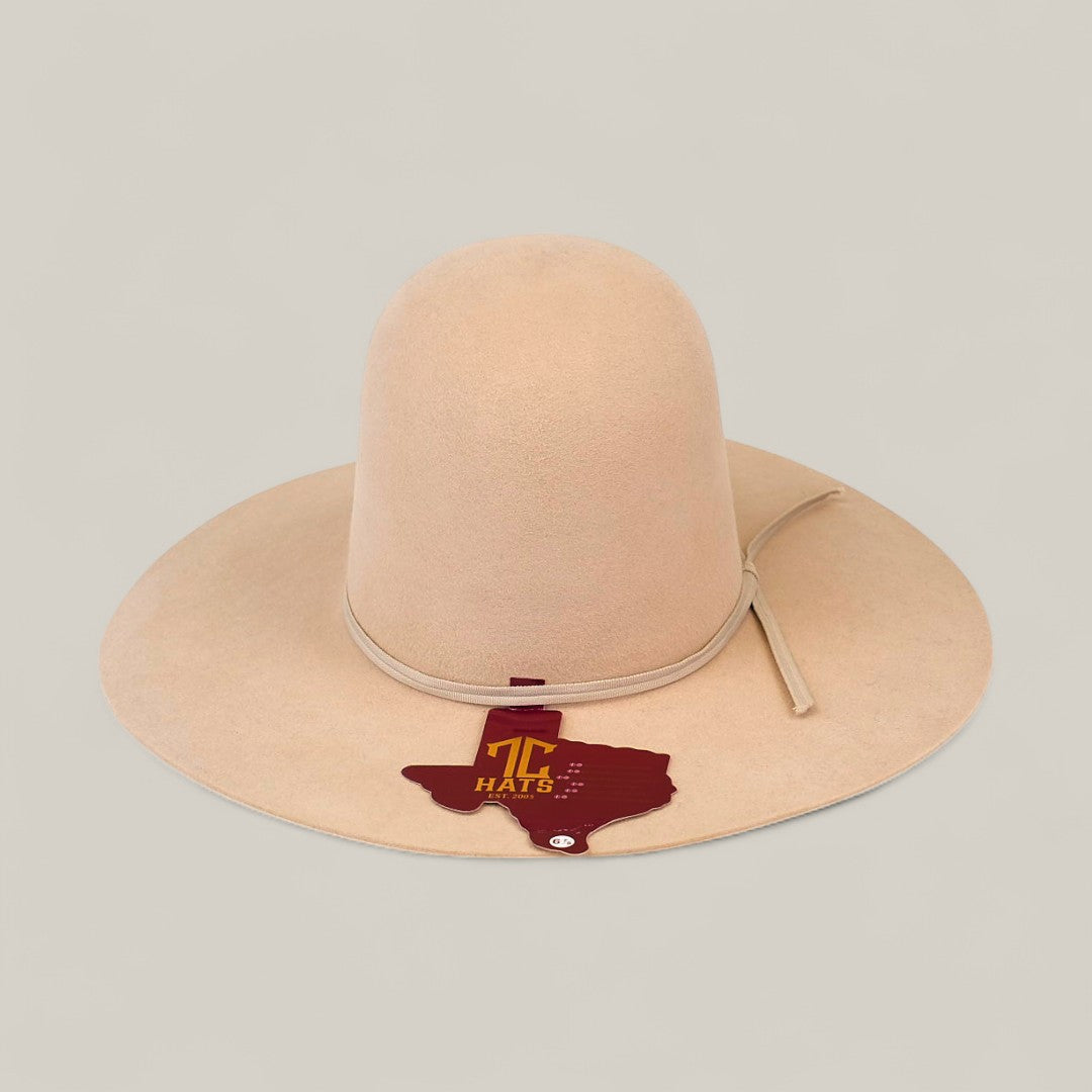 The 10x Belly - TC Hats is a light beige, wide-brimmed Western hat with a shapeable crown and a decorative Texas-shaped tag featuring T HATS and a star design, shown against a neutral backdrop.