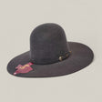 The 4X Gray - TC Hats is a wide-brimmed, dark gray felt Western hat with an open crown Texana style, decorative band and gold buckle, maroon tag on the brim, shown on a plain light background.