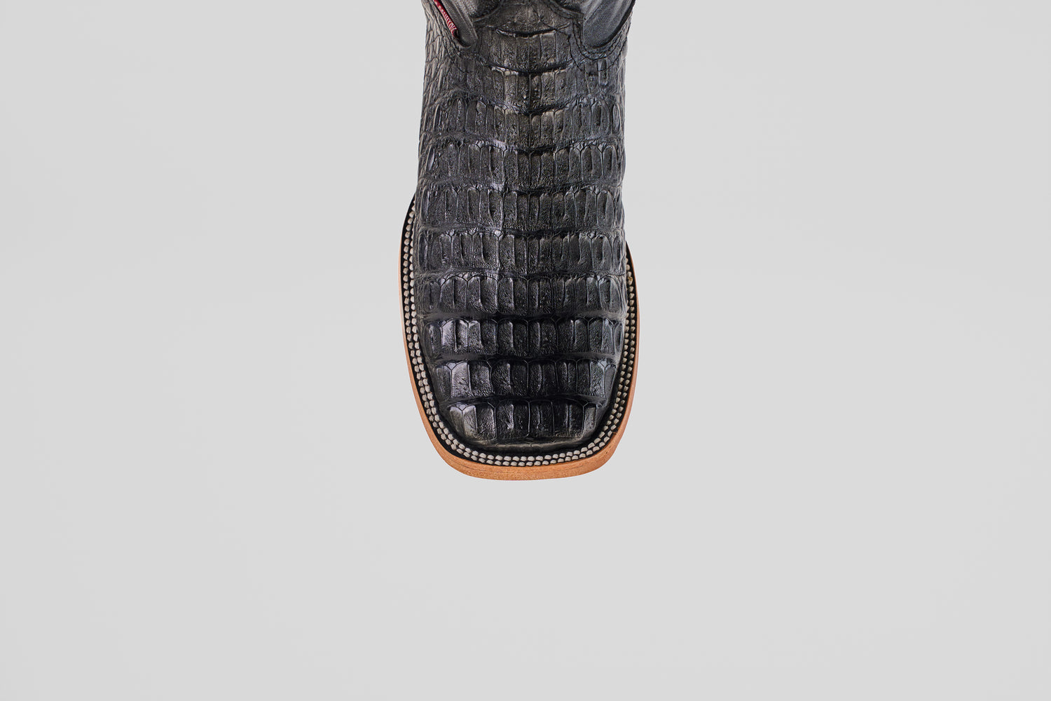 A close-up, top-down view of the Exotic Caiman Horn Back - Black - Square Toe boot highlights its textured reptile-like pattern and decorative welt stitching, showcasing the distinctive style of square toe boots.