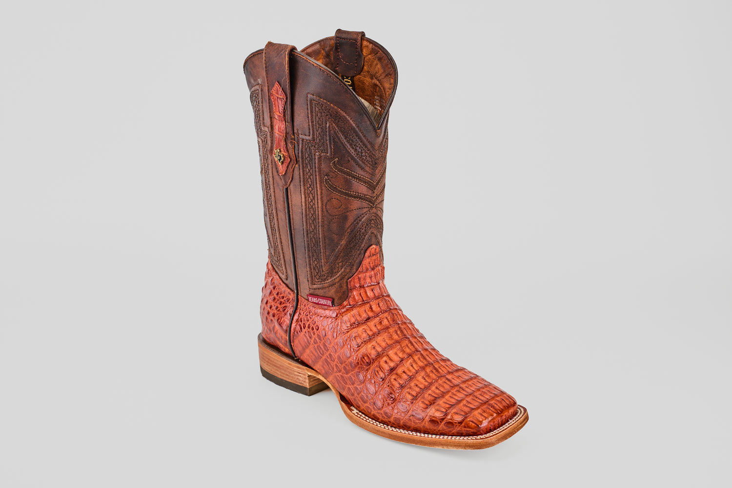 The Exotic Caiman Horn Back - Brandy - Square Toe boot features intricate stitching, a textured horn back pattern, square toe, and wooden heel, displayed singly on a plain light gray background.
