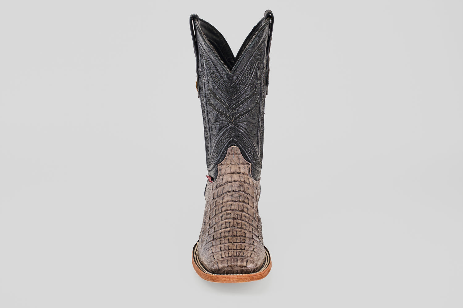 The Exotic Caiman Horn Back - Serpentine - Square Toe boot is shown from the front, displaying a textured reptile-like lower, dark stitched shaft, and light brown sole—a classic western look against a plain background.