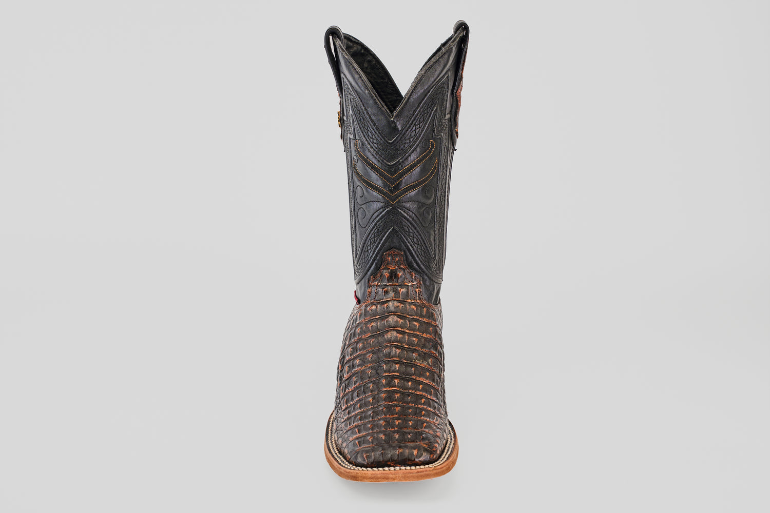 The Exotic Caiman Horn Back - Roma - Square Toe boot features a textured brown caiman-like lower and a black stitched upper shaft, displayed front-facing against a plain light background.