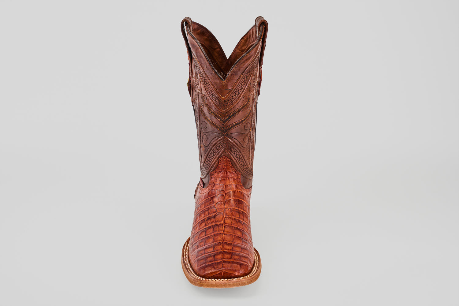 The Exotic Caiman Belly - Brandy - Square Toe boot, featuring detailed stitching and textured caiman leather, is shown from the front on a plain light gray background.