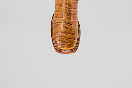 A close-up of the Exotic Caiman Belly - Camel - Square Toe boot shows its brown caiman leather with a textured, crocodile-like pattern and square tip, set against a plain white background.