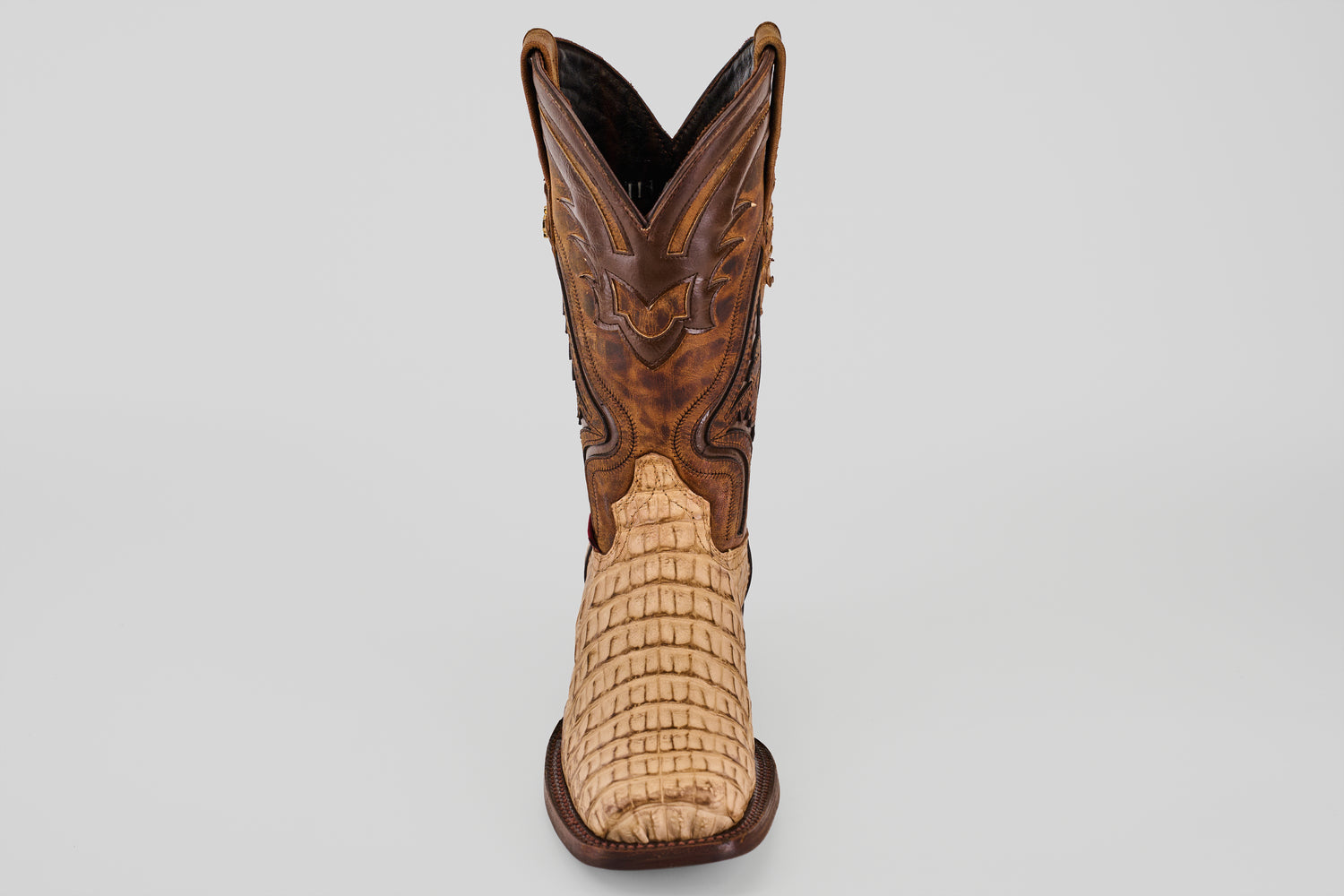 The Exotic Caiman Hornback - Orix - Rodeo Toe boot features a light tan, textured lower and a darker brown, intricately stitched upper, displayed front-facing against a plain white background.