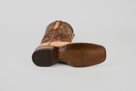 A single Exotic Caiman Hornback - Orix - Rodeo Toe boot lies on its side, showcasing the wooden sole with branding and tread, decorative stitching, and a square toe against a plain light gray background.