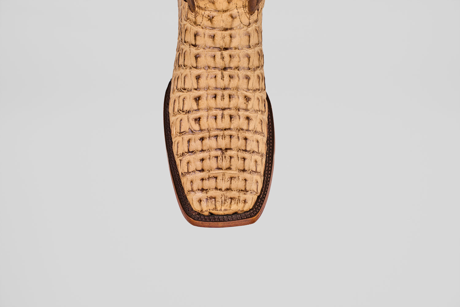 Close-up of the front of the Exotic Caiman Hornback - Antique - Rodeo Toe boot, featuring light brown caiman leather with a textured, woven pattern and darker trim, shown against a plain white background.