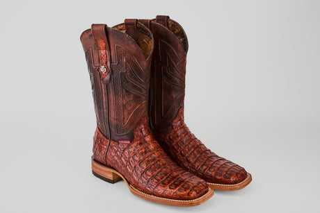 A pair of Exotic Caiman Horn Back - Smoke Cogñac square toe boots, featuring textured caiman leather and intricate stitching, displayed on a plain light gray background.