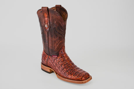 The Exotic Caiman Horn Back - Smoke Cogñac Square Toe cowboy boot features a brown textured pattern, wooden heel, and decorative stitching, showcased on a light gray background.
