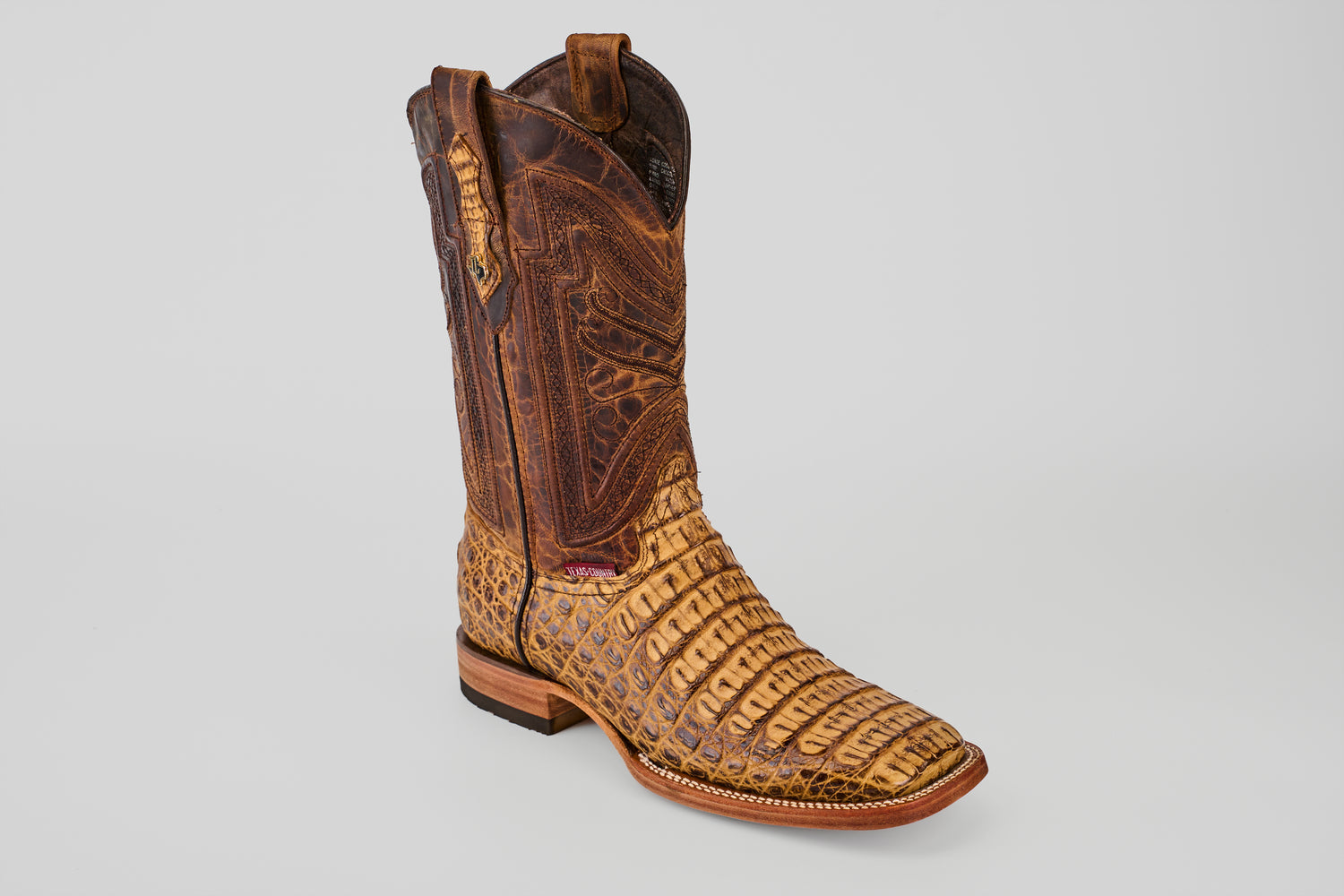 The Exotic Caiman Horn Back - Biza Camel - Square Toe boot showcases a textured light tan and brown alligator pattern foot with a darker, intricately stitched shaft, displayed on a plain gray background.