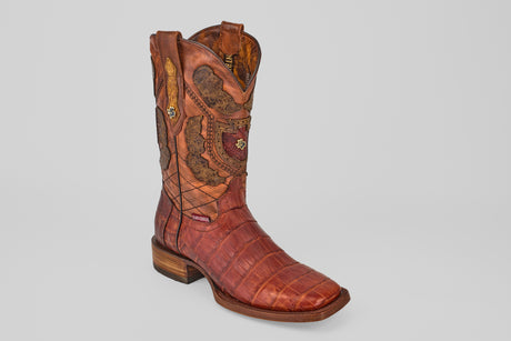 The Exotic Alligator Tail - Brick - Square Toe cowboy boot, crafted from genuine brown alligator leather with decorative stitching and a wooden heel, is displayed on a light gray background.