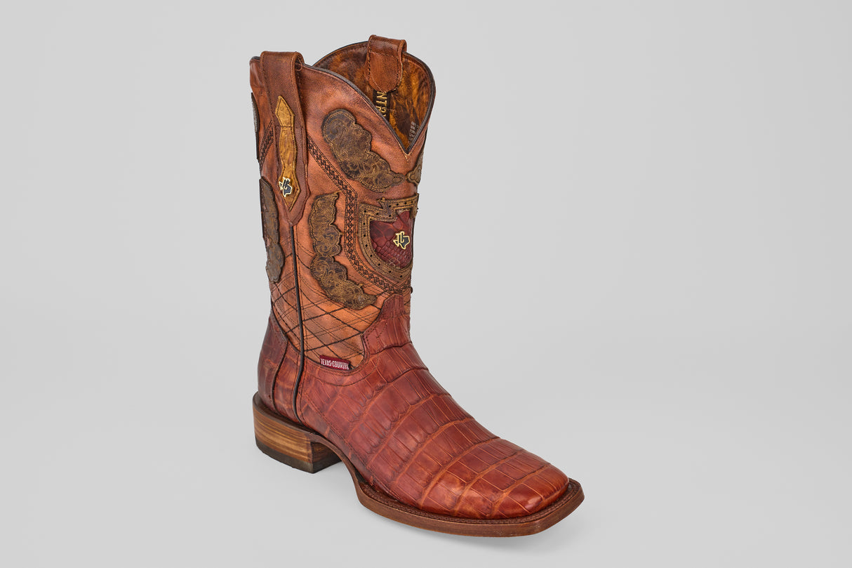 The Exotic Alligator Tail - Brick - Square Toe cowboy boot, crafted from genuine brown alligator leather with decorative stitching and a wooden heel, is displayed on a light gray background.