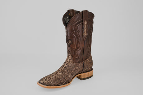 The Exotic Full Quilt Ostrich Leg - Matte Orix - Square Toe boot, featuring a dark brown leather upper, light brown textured lower, wooden sole, and low heel, is shown on a plain light gray background.