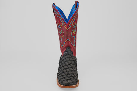 The Dodge - Matte Black - Square Toe boot features a textured black Pirarucu leather foot, square toe, brown sole, and a tall red shaft with decorative stitching and blue lining. Mens luxury boot shown facing forward on a plain background.