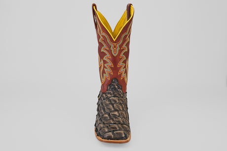 A single Butch - Caramel - Square Toe cowboy boot with a textured dark brown Pirarucu leather foot and a tall red shaft featuring yellow and beige stitching, viewed from the front against a plain light background.
