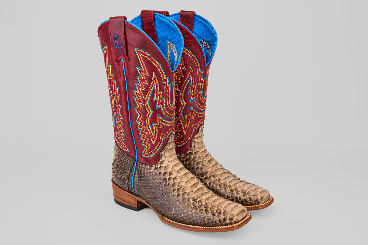 The Barlow - Taupe - Square Toe boots feature taupe python leather, vibrant red, blue, and yellow stitching on tall shafts, wooden heels, blue lining, and a classic square toe design.