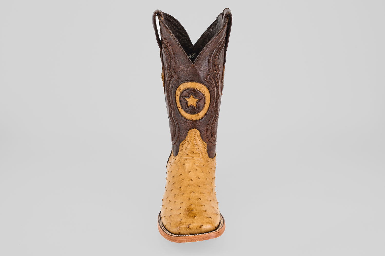 The Exotic Full Quilt Ostrich - Fawn - Square Toe boot features a tan ostrich foot, dark brown shaft, and a star emblem patch, offering timeless cowboy style with premium craftsmanship.