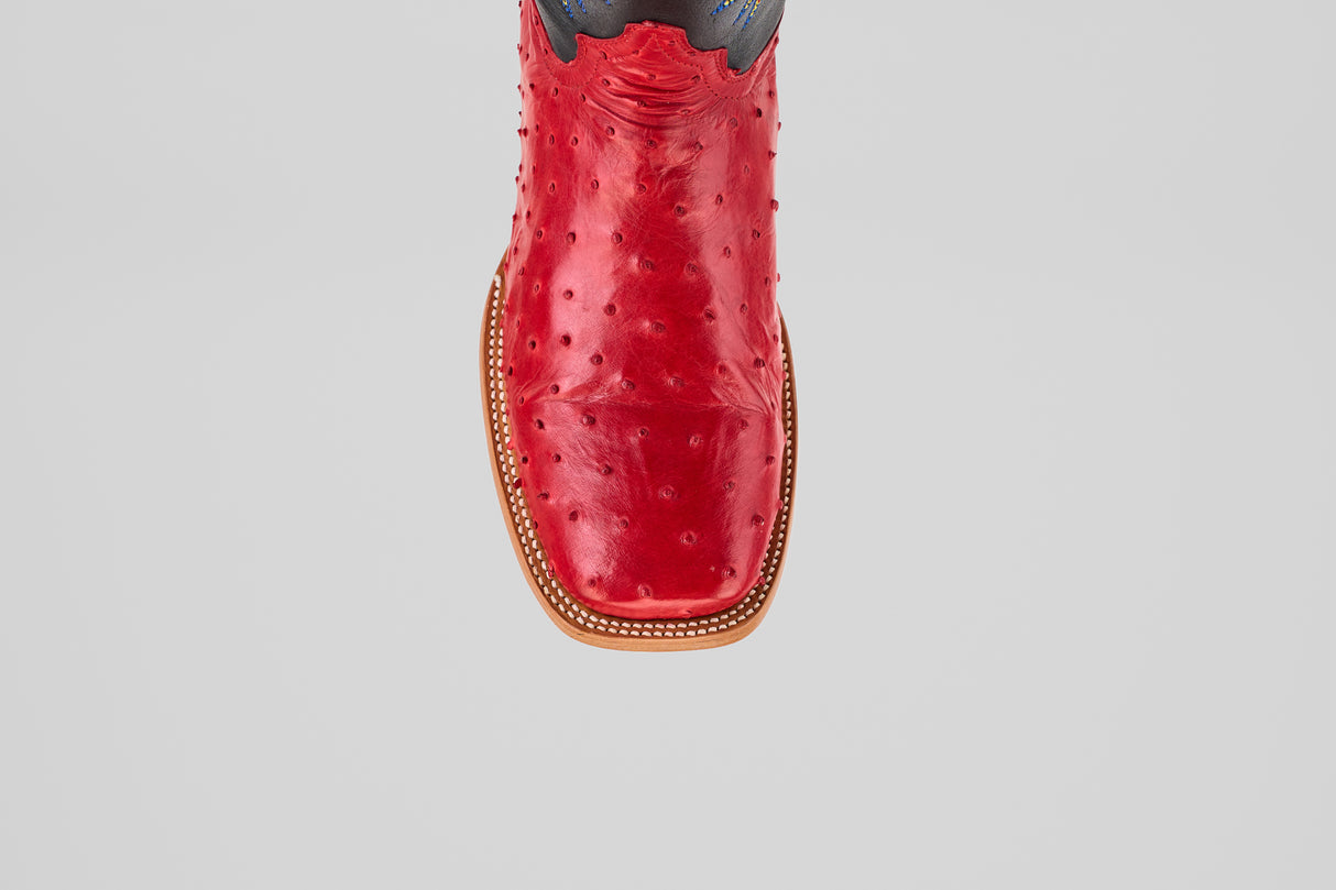 A close-up top view of Crowley - Red - Square Toe boots, featuring vibrant red smooth leather with a decorative stitched border inspired by classic Ostrich boots, set against a plain light gray background.