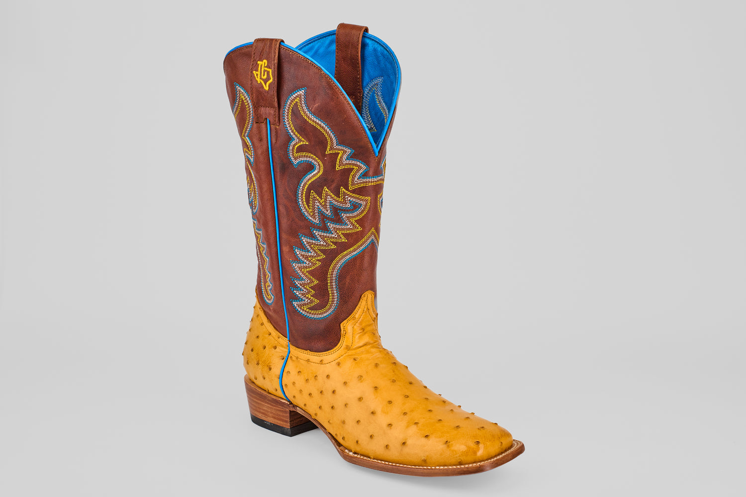The Ransom - Buttercup - Square Toe Boot from the Platinum Collection features a tan ostrich leather foot, brown shaft with blue and yellow stitching, and a blue lining, shown on a light gray background.