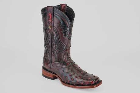 The Exotic Ostrich - Black Cherry - Rodeo Toe features decorative stitching, red accents, and a textured ostrich leather surface, showcased on a light gray background—an eye-catching exotic boot.