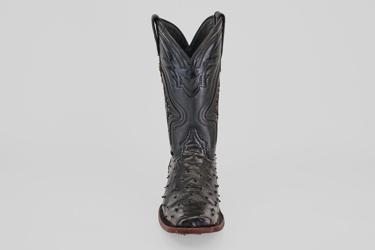 The Exotic Ostrich - Black - Rodeo Toe is a single black cowboy boot featuring a textured, ostrich-style surface and a pointed rodeo toe, shown from the front against a plain white background.