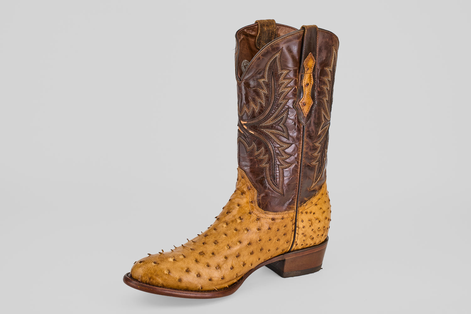 The Exotic Full Quilt Ostrich - Paja - Round Toe features brown leather and light tan ostrich skin with signature raised quills and decorative stitching, presented on a plain gray background.