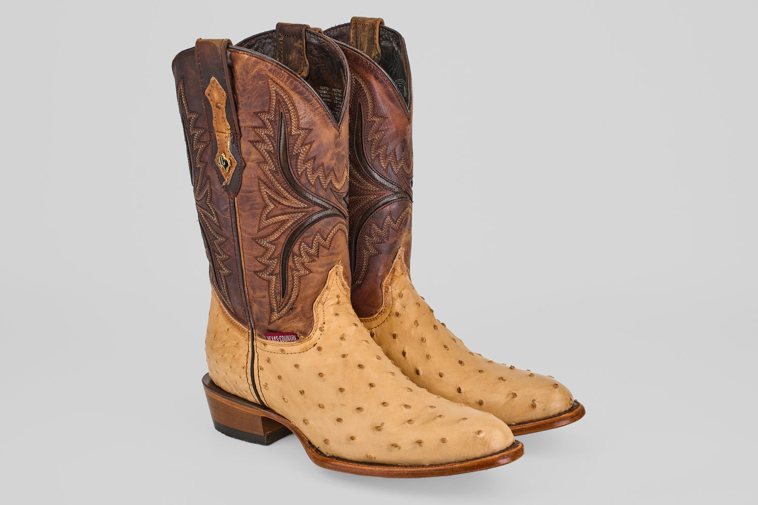 The Exotic Full Quilt Ostrich - Orix - Round Toe showcases light tan quilted ostrich leather on the foot and dark brown, intricately stitched shafts, all set against a plain light gray background.