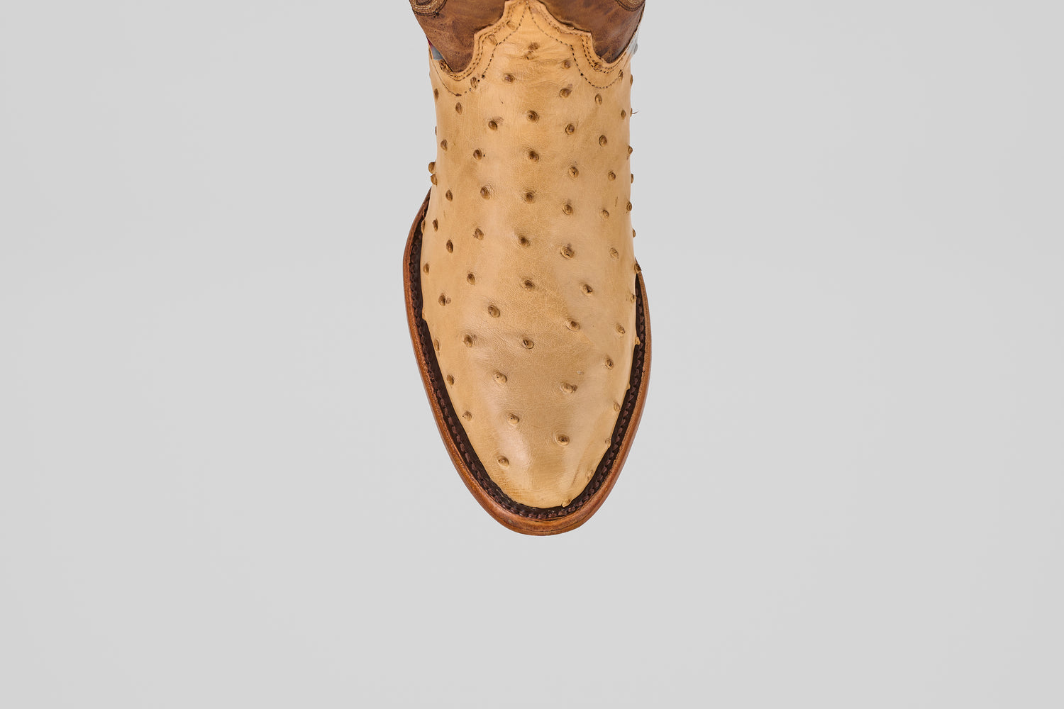 The Exotic Full Quilt Ostrich - Orix features tan ostrich leather with round toe, brown welt stitching, and full quill bumps—showcasing handcrafted Western quality. Photographed from above on a white background.