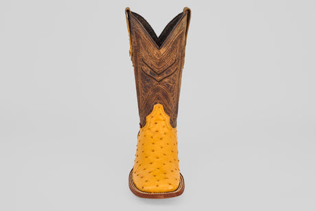 The Exotic Full Quilt Ostrich - Buttercup- Square Toe features a yellow ostrich leather foot and a tall, brown, intricately stitched shaft—shown facing forward on a plain gray background—for handcrafted western boot enthusiasts.