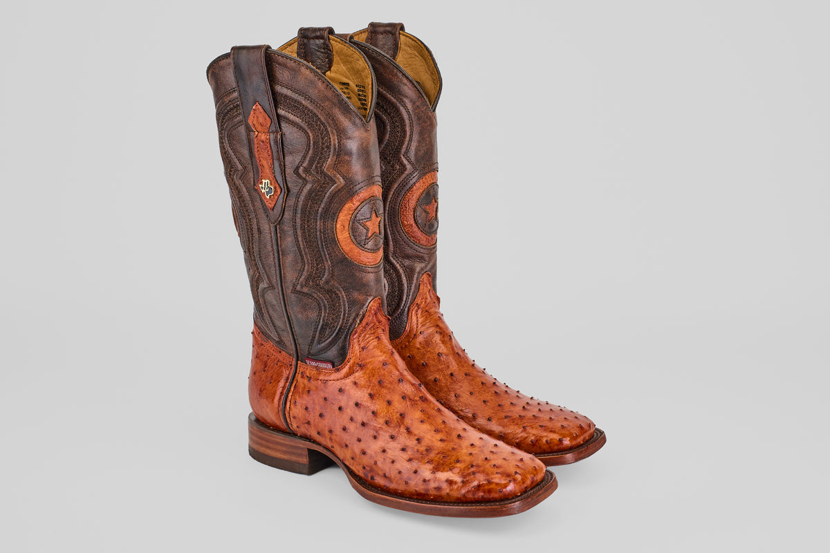 The Austin - Brandy - Square Toe boots feature brown leather uppers with decorative stitching and orange Avestruz Brandy ostrich leather lowers, displayed on a plain light gray background.