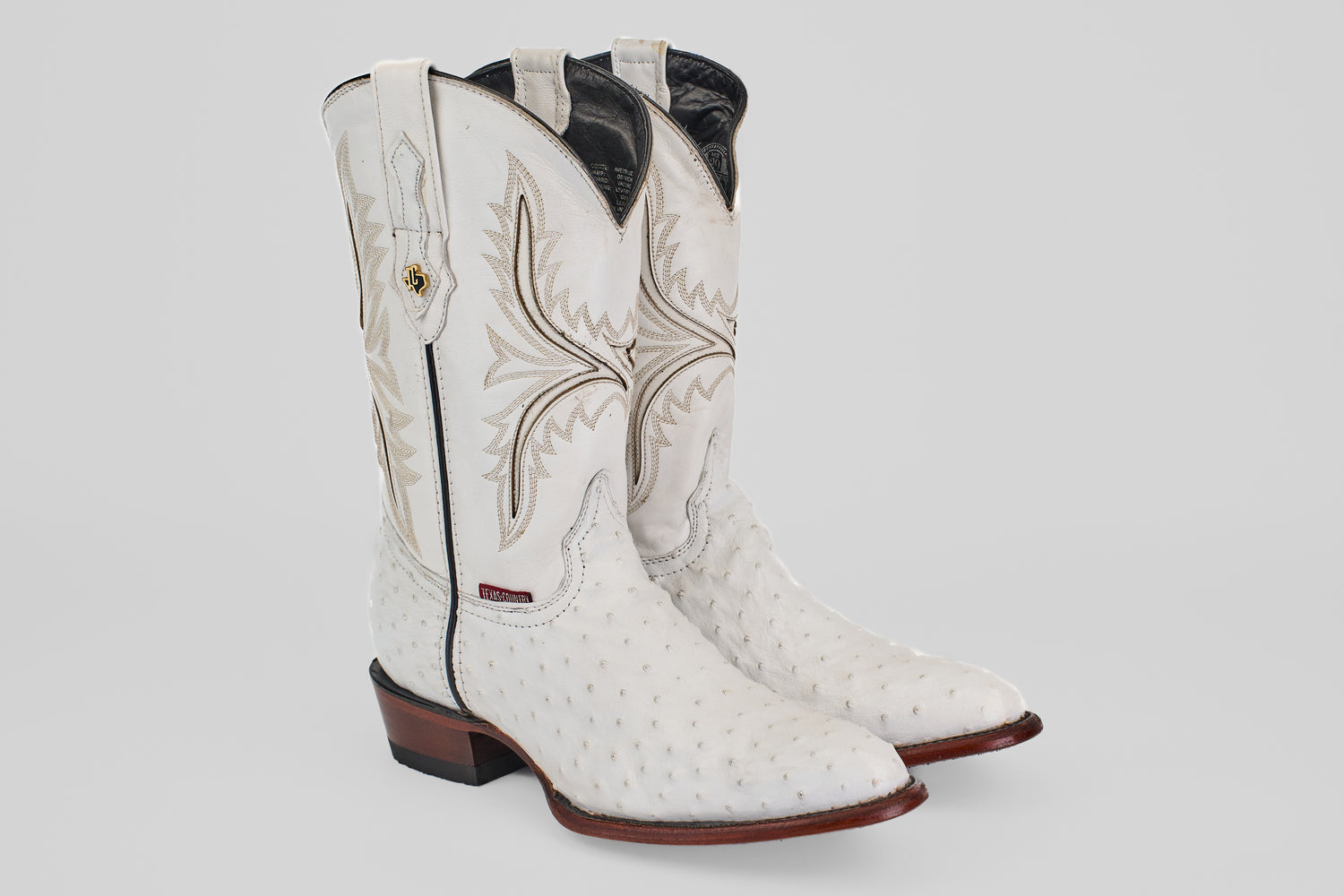 A pair of Austin - White - Round Toe boots, featuring decorative stitching, textured leather, round toes, and brown stacked heels with distinctive oval patterns, displayed on a plain light background.