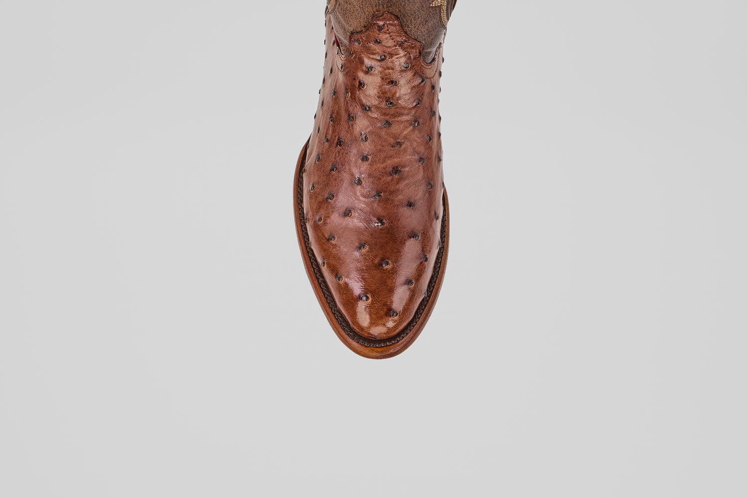 A close-up, top-down view of the toe and upper of the Austin - Brown - Round Toe cowboy boot in brown ostrich leather, shown against a plain light gray background.