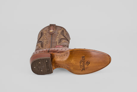 An Austin - Brown - Round Toe cowboy boot lies on its side, showing the sole with the TEXAS LEGEND logo and upper decorative stitching, set against a plain light gray background.