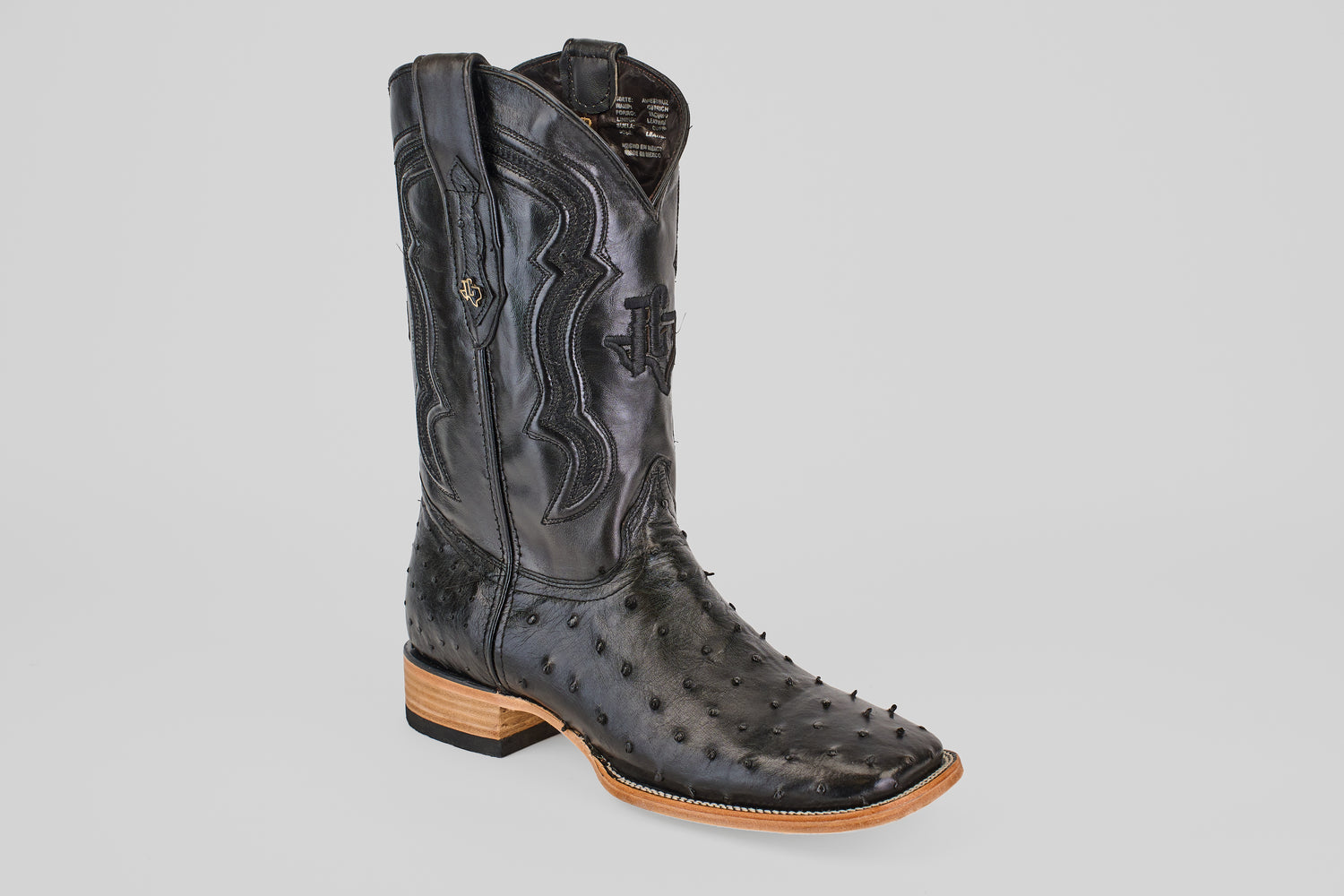 The Austin - Black - Square Toe cowboy boot features textured black leather with an avestruz pattern, detailed stitching, a square toe, and a light stacked heel, shown against a plain light background.