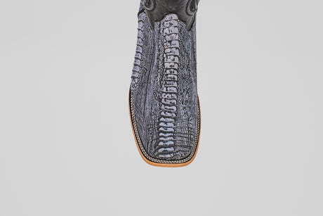 A close-up of the Austin Leg - Blue Jean - Square Toe men's cowboy boot shows its gray and black reptile-like pattern, brown stitched sole, and blue jean finish against a plain white background.