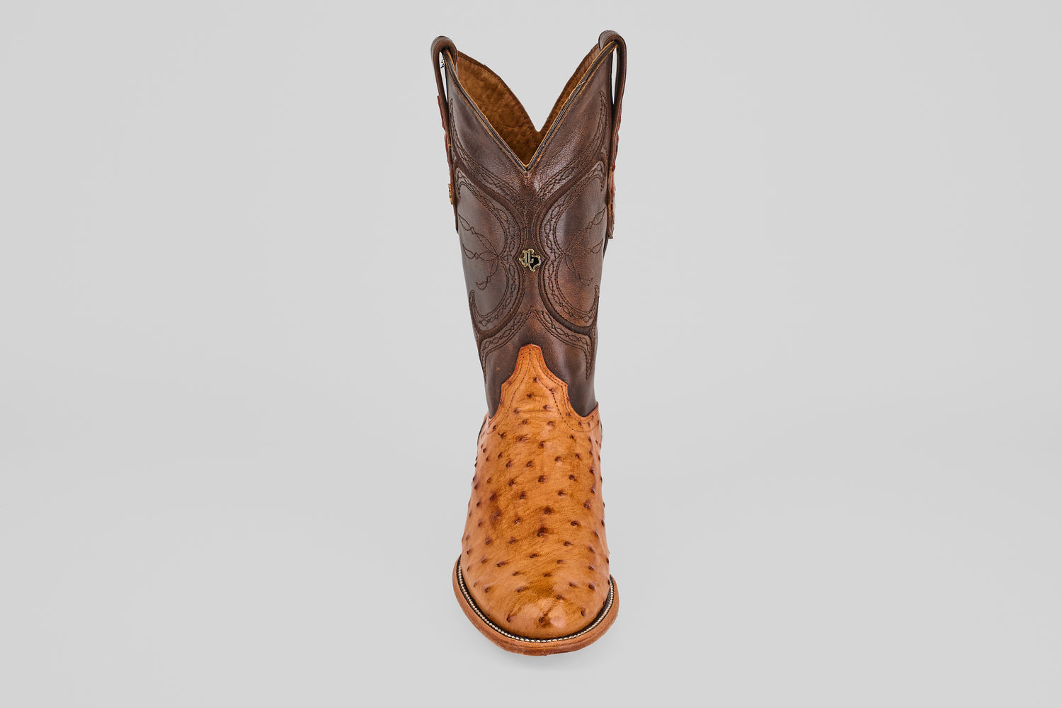 The Austin - Brandy - Roper Toe is a men's cowboy boot featuring a brown leather upper and light tan textured ostrich leather lower, shown upright on a plain white background. Ideal for fans of classic ostrich leather boots.