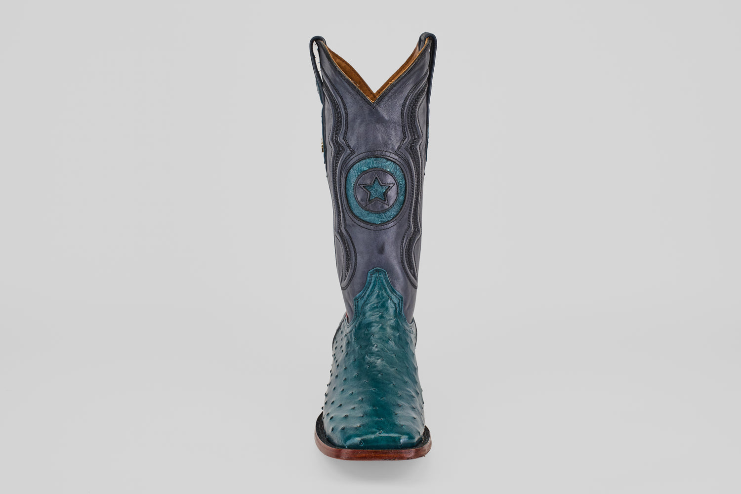 The Austin - Gasoline Green - Square Toe men’s western boot features a teal ostrich leather foot and a dark blue shaft with star and circular stitching, shown from the front on a white background—ideal for ostrich leather boot enthusiasts.